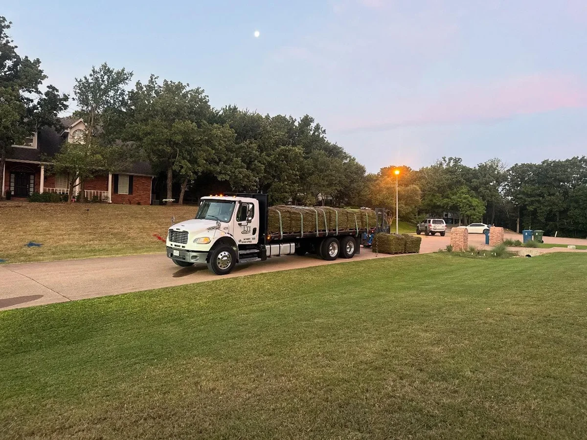 A flatbed loaded with sod beside a residential driveway
